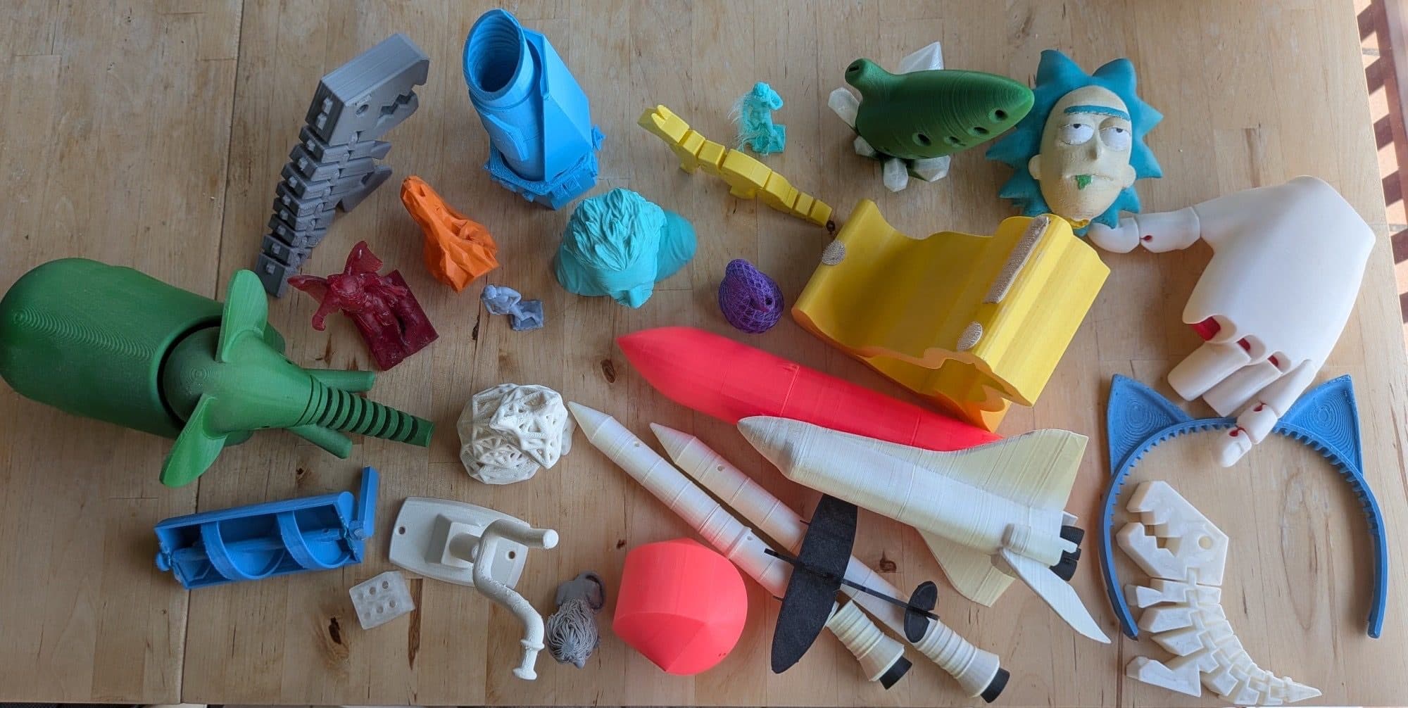 A table covered in 3D prints: a space shuttle, rockets, a hand, an ocarina and more