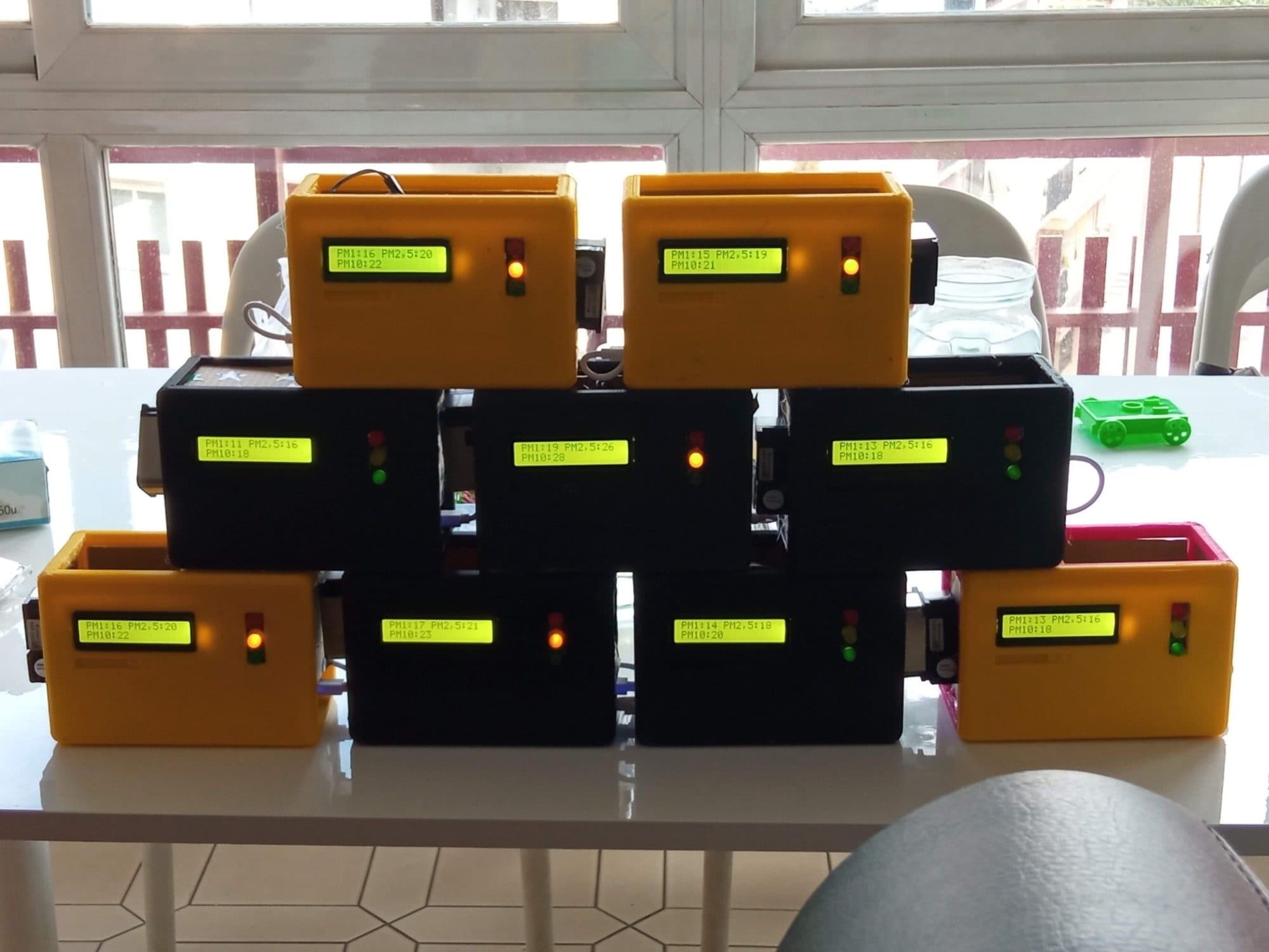 Ten air quality sensors in 3D-printed cases, their screens showing particle readings